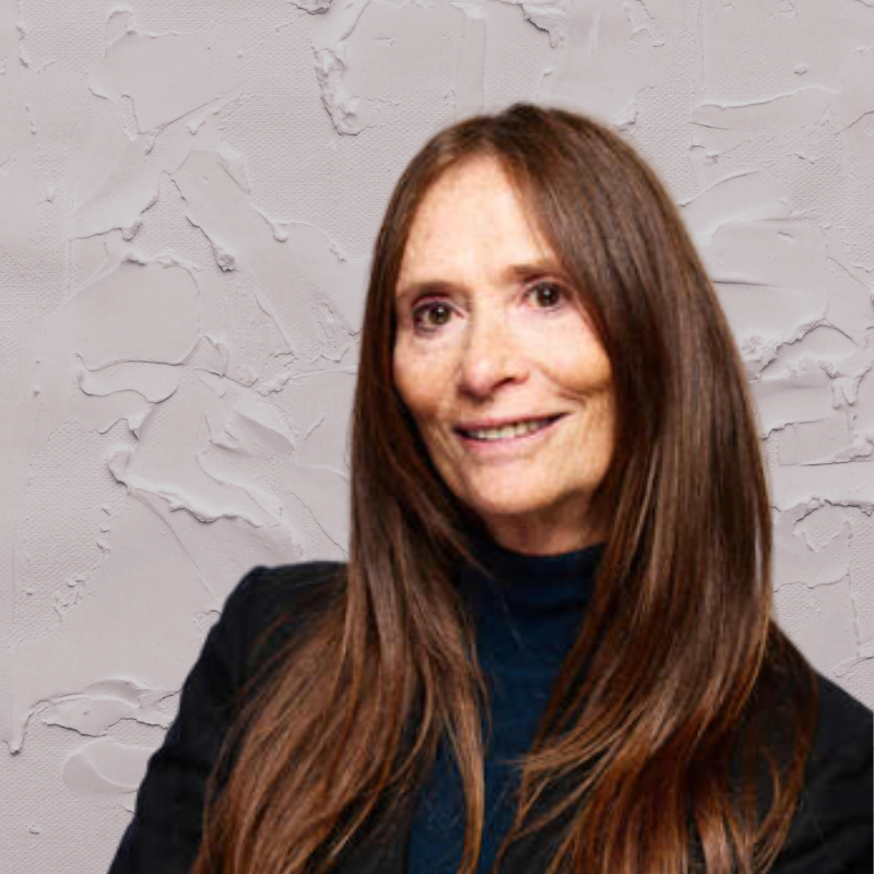 A woman with long brown hair wearing a black jacket and dark turtleneck stands in front of a textured light gray wall, representing Memcyco at Datos Insights FinCrime Forum 2025.